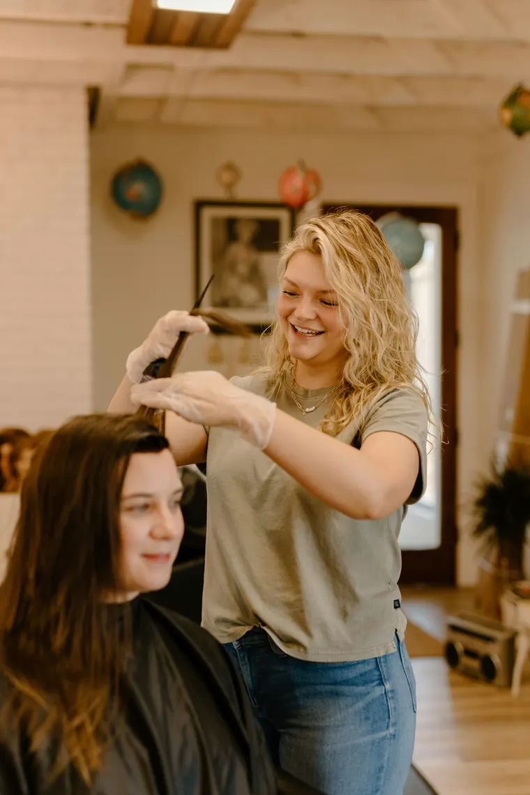 Coiffeuse réalisant une mise en plis à domicile, ambiance chaleureuse