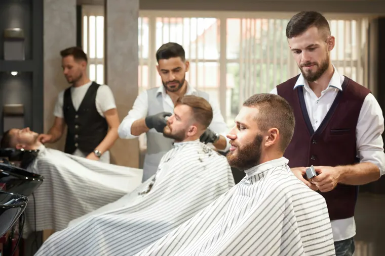 Barbier au travail sur un client installé au fauteuil