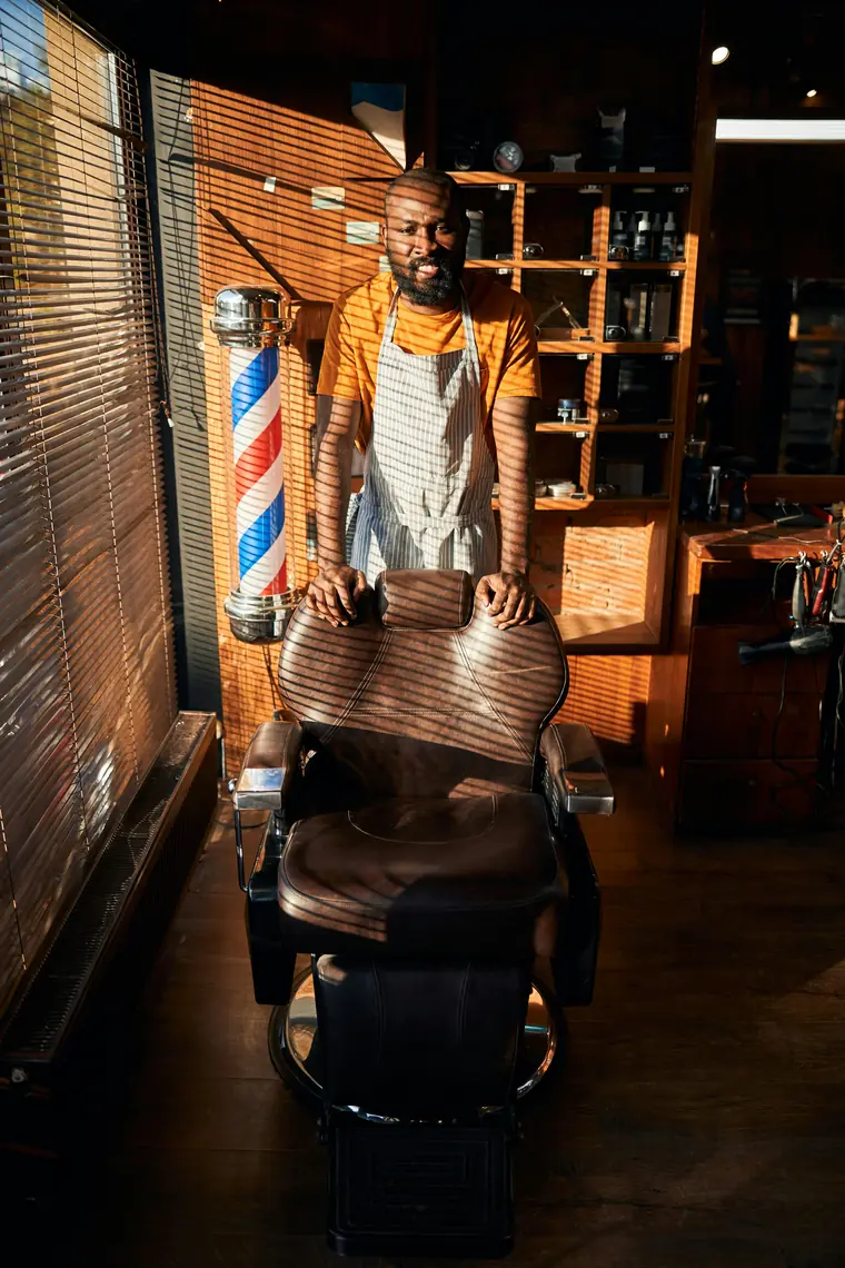 Barbier dans son salon, debout derrière son fauteuil