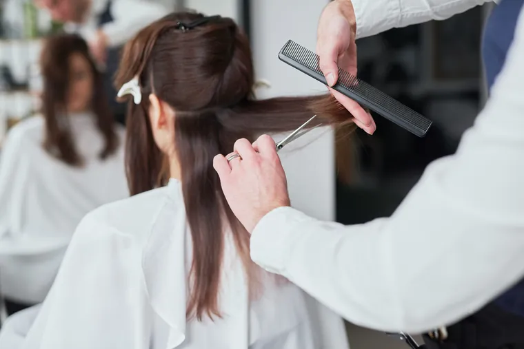 Coiffeuse coupant les cheveux d’une cliente dans un salon lumineux